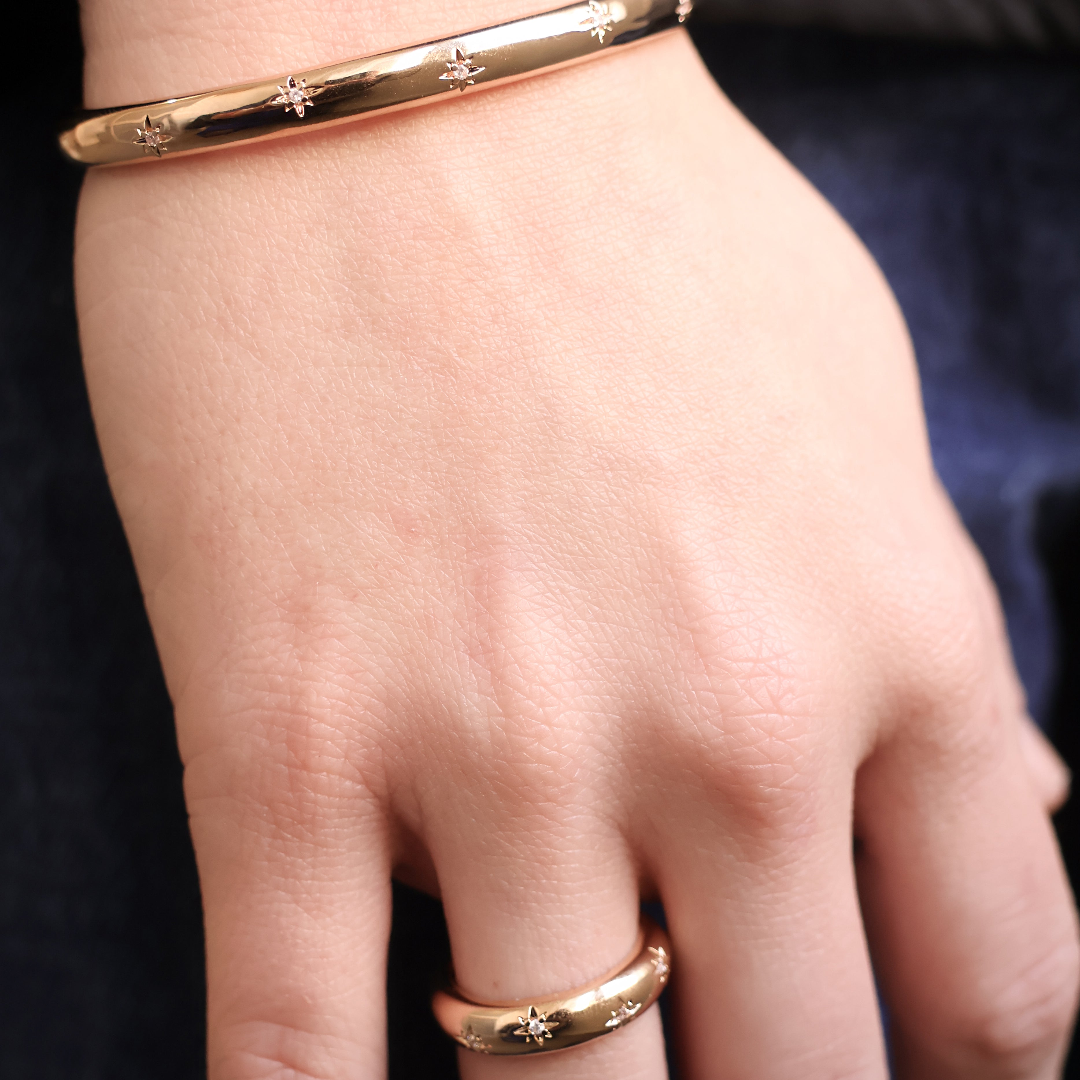 Bague Aria en plaqué or 18 carats – Un bijou raffiné orné de délicates étoiles gravées, chacune sublimée par un oxyde de zirconium scintillant. Son design élégant et moderne apporte une touche de magie et d’éclat à vos tenues. Féminine et sophistiquée, cette bague intemporelle est disponible en plusieurs tailles (50 à 60). Conçue en laiton avec un placage 5 microns et poinçon garantissant qualité et durabilité.