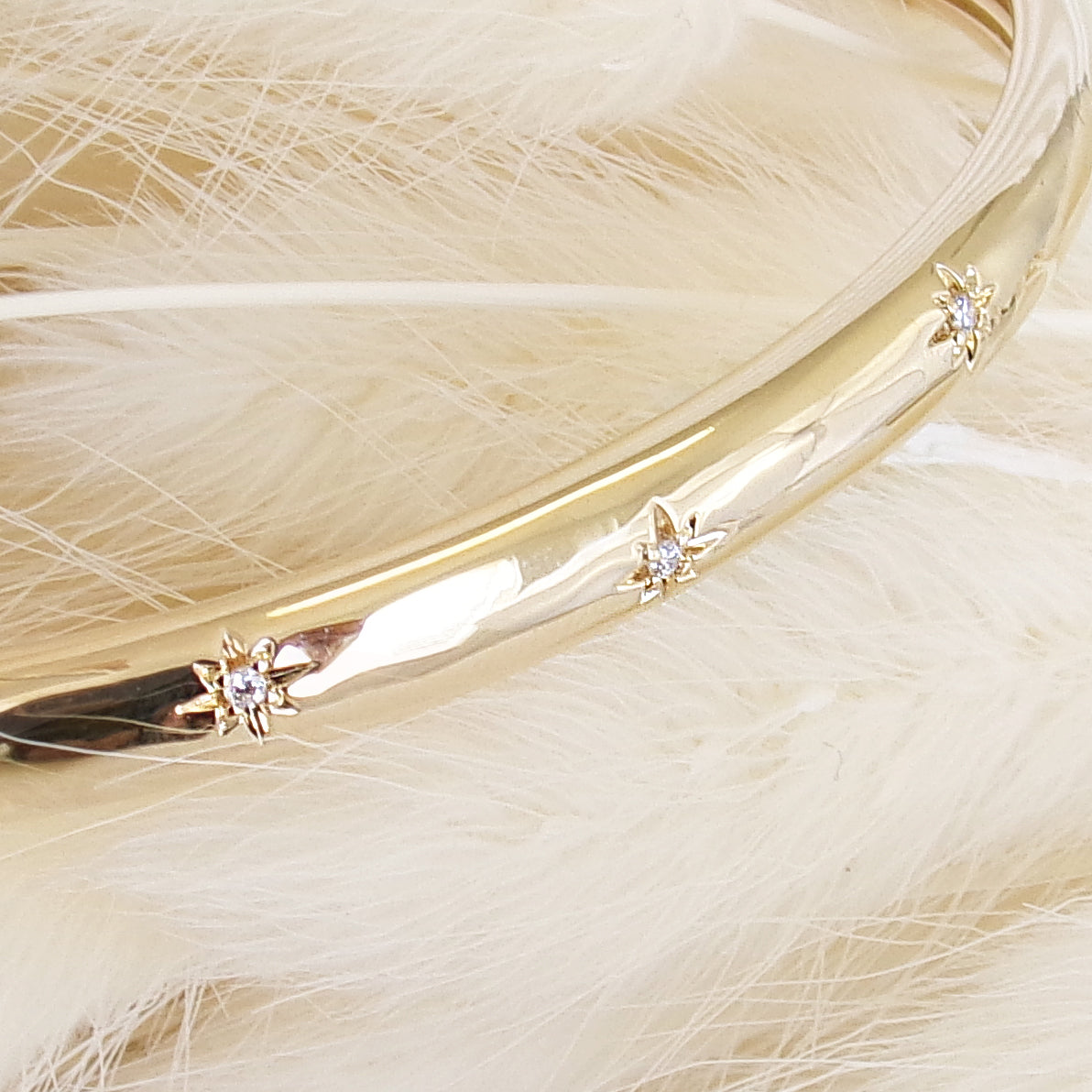 Bracelet jonc ouvert Aria en plaqué or 18 carats – Plongez dans un univers magique avec ce bijou raffiné, orné de deux étoiles serties d’oxydes de zirconium scintillants. Son design élégant sublime votre style et apporte une touche lumineuse à toutes vos tenues. Diamètre : 58 mm. Conçu en laiton avec un placage 3 microns et poinçon garantissant qualité et durabilité.