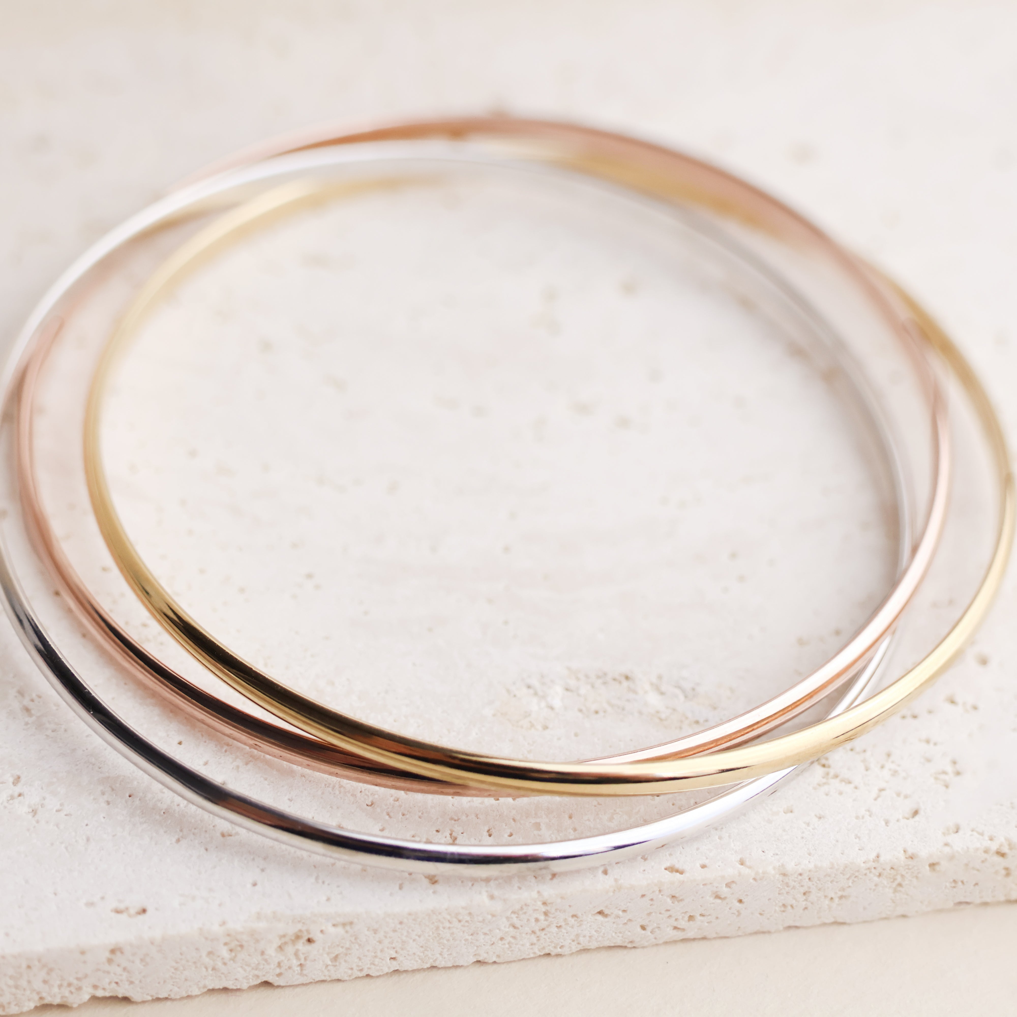 Set de 3 joncs entrelacés en plaqué or 18 carats – Un indispensable alliant élégance et modernité avec ses trois tons : or jaune, or rose et argenté (plaqué or 18 carats rhodié). Un design intemporel parfait pour sublimer votre poignet avec finesse. Diamètre 66 mm, largeur de chaque jonc 3 mm. Conçu en laiton avec un placage 3 microns et poinçon garantissant qualité et durabilité.