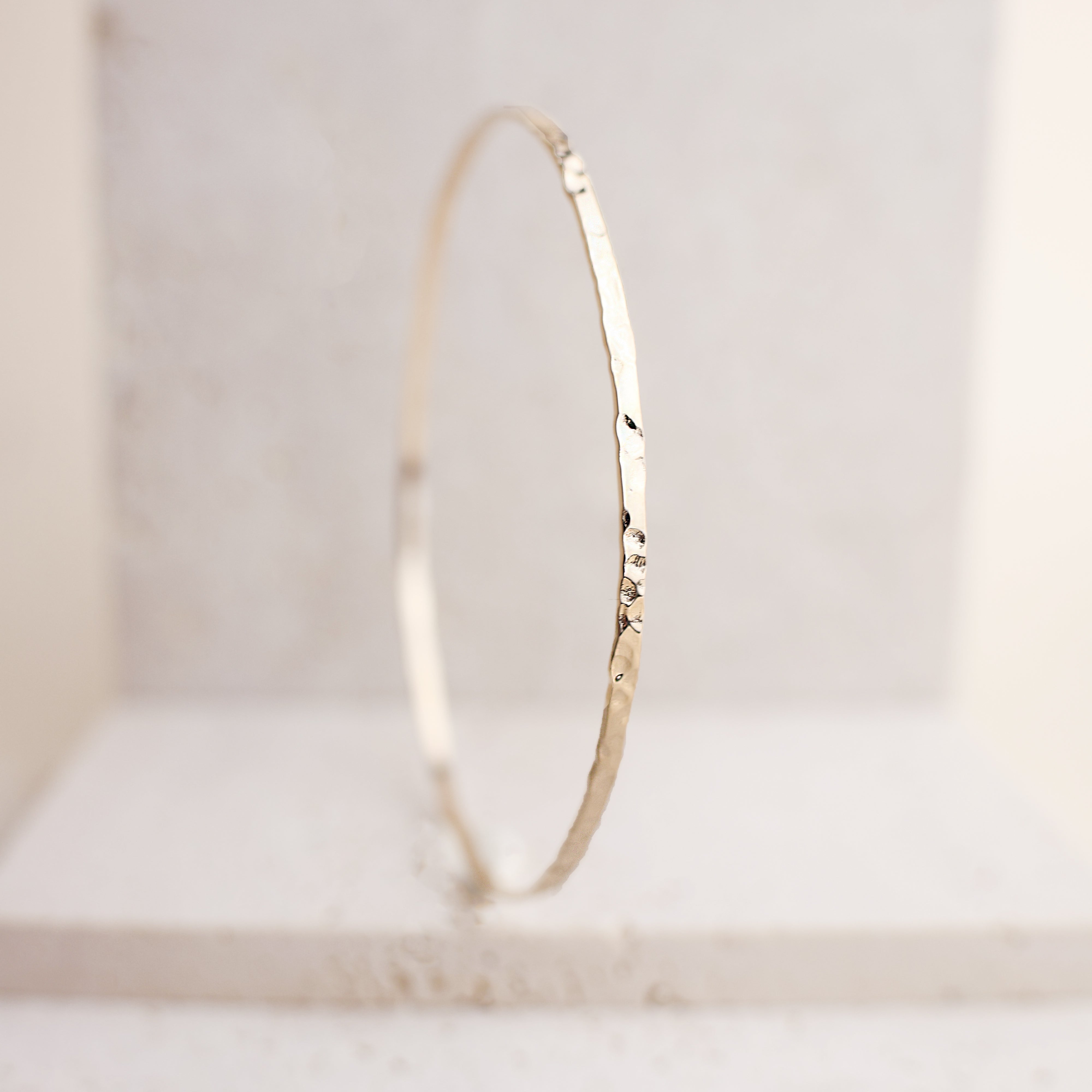 Bracelet Rosie en plaqué or 18 carats – Jonc élégant avec une finition martelée à l'extérieur et un intérieur lisse, offrant un jeu subtil de textures. Son éclat raffiné apporte une touche lumineuse à vos tenues et sublime votre style avec finesse. Diamètre 62 mm, conçu en laiton avec un placage 3 microns et poinçon garantissant qualité et durabilité.