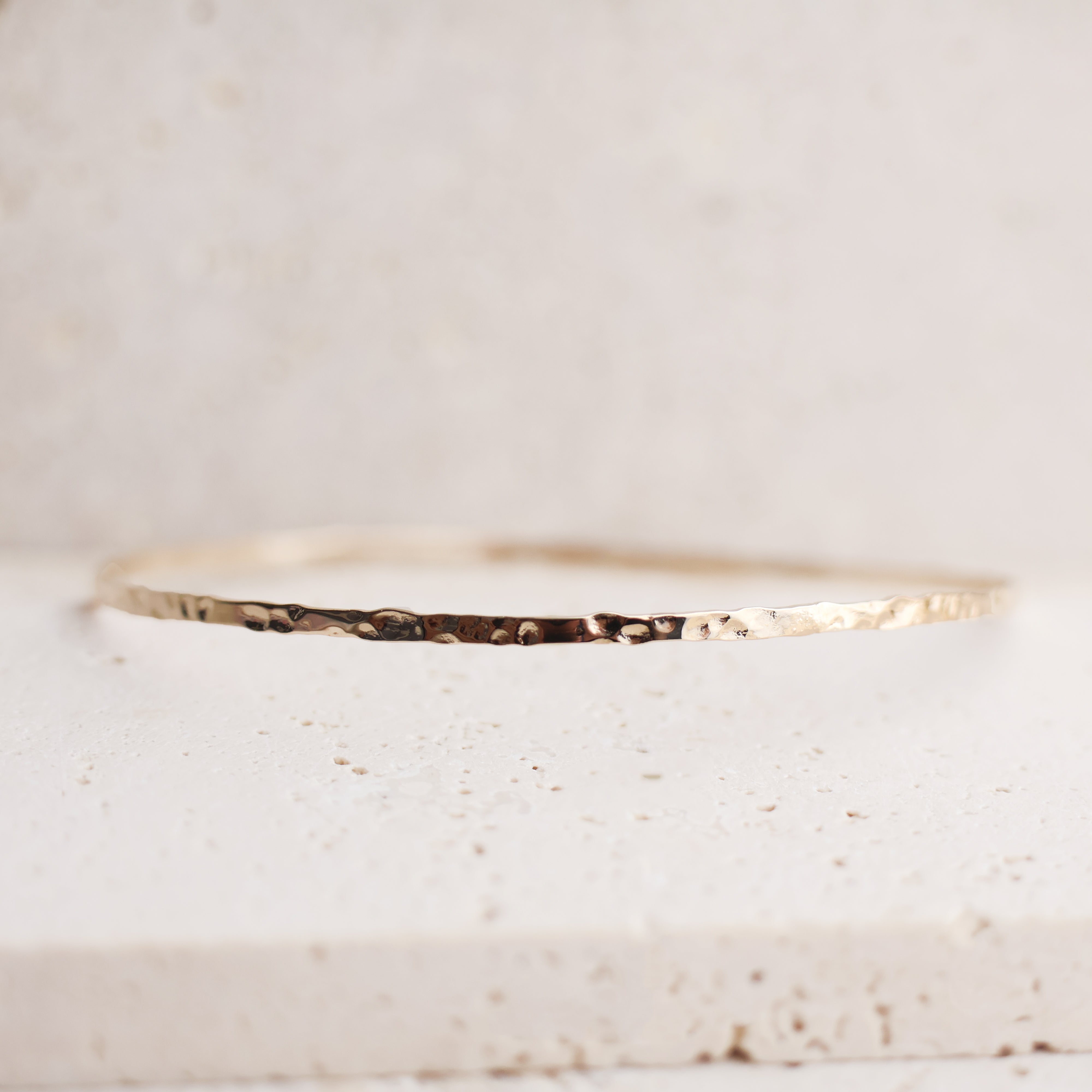 Bracelet Rosie en plaqué or 18 carats – Jonc élégant avec une finition martelée à l'extérieur et un intérieur lisse, offrant un jeu subtil de textures. Son éclat raffiné apporte une touche lumineuse à vos tenues et sublime votre style avec finesse. Diamètre 62 mm, conçu en laiton avec un placage 3 microns et poinçon garantissant qualité et durabilité.