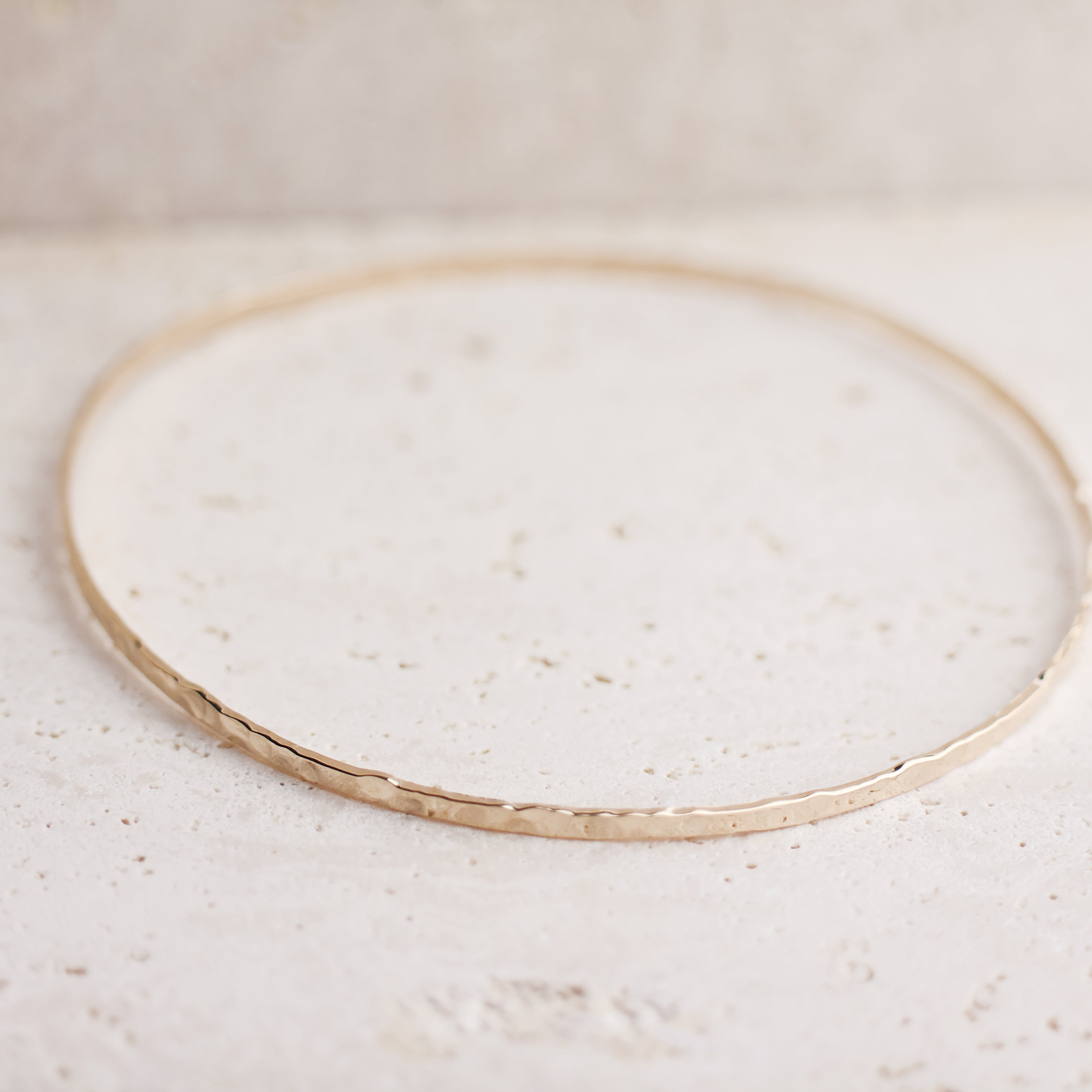 Bracelet Rosie en plaqué or 18 carats – Jonc élégant avec une finition martelée à l'extérieur et un intérieur lisse, offrant un jeu subtil de textures. Son éclat raffiné apporte une touche lumineuse à vos tenues et sublime votre style avec finesse. Diamètre 62 mm, conçu en laiton avec un placage 3 microns et poinçon garantissant qualité et durabilité.