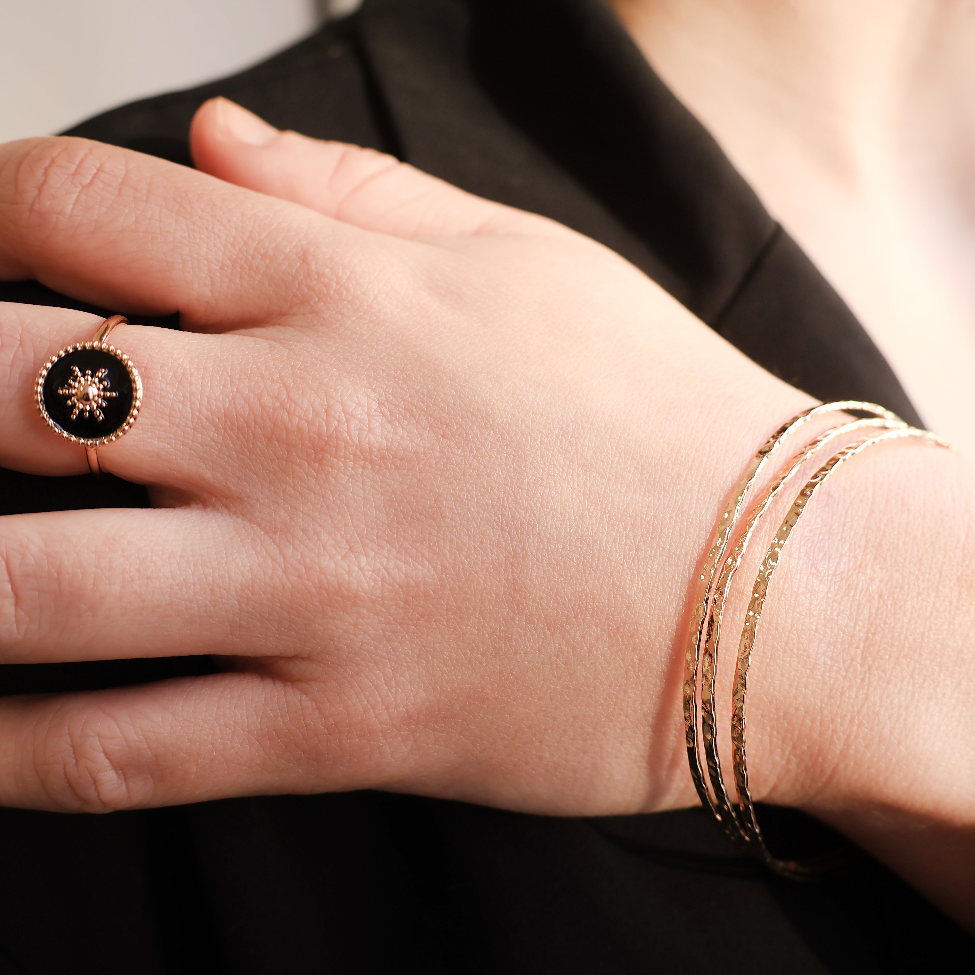 Bracelet Rosie en plaqué or 18 carats – Jonc élégant avec une finition martelée à l'extérieur et un intérieur lisse, offrant un jeu subtil de textures. Son éclat raffiné apporte une touche lumineuse à vos tenues et sublime votre style avec finesse. Diamètre 62 mm, conçu en laiton avec un placage 3 microns et poinçon garantissant qualité et durabilité.