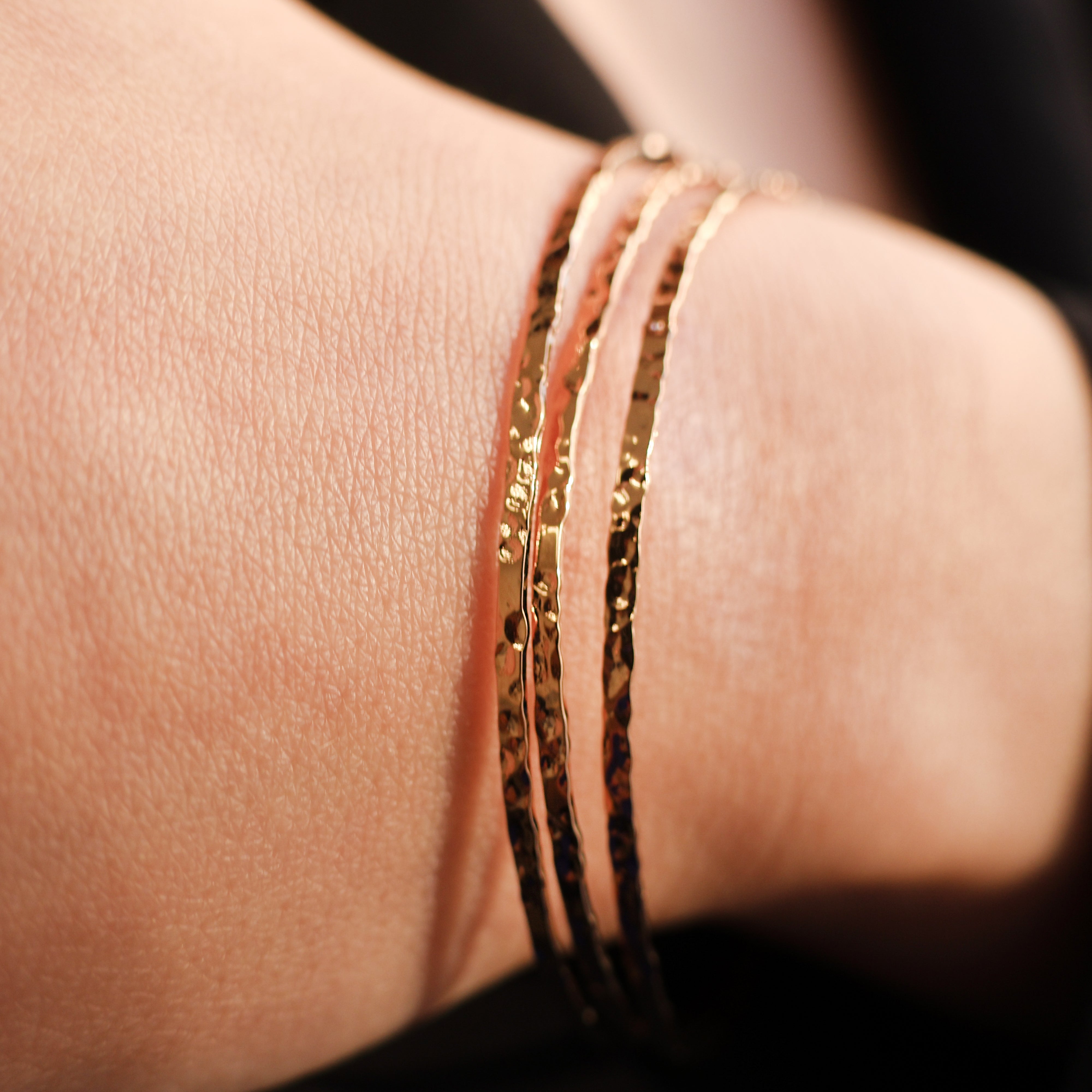 Bracelet Rosie en plaqué or 18 carats – Jonc élégant avec une finition martelée à l'extérieur et un intérieur lisse, offrant un jeu subtil de textures. Son éclat raffiné apporte une touche lumineuse à vos tenues et sublime votre style avec finesse. Diamètre 62 mm, conçu en laiton avec un placage 3 microns et poinçon garantissant qualité et durabilité.