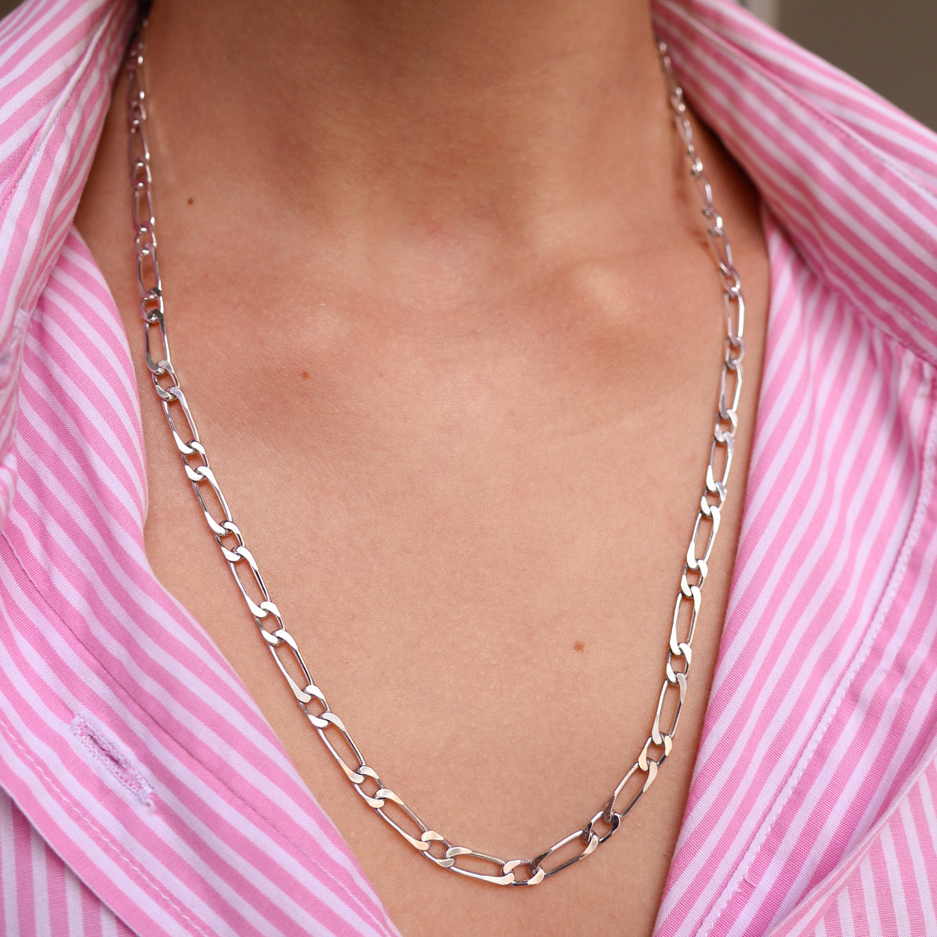 Chaîne en argent 925 rhodié portée sur un col de chemise rayé rose, bijou unisexe à mailles plates, indémodable et minimaliste.