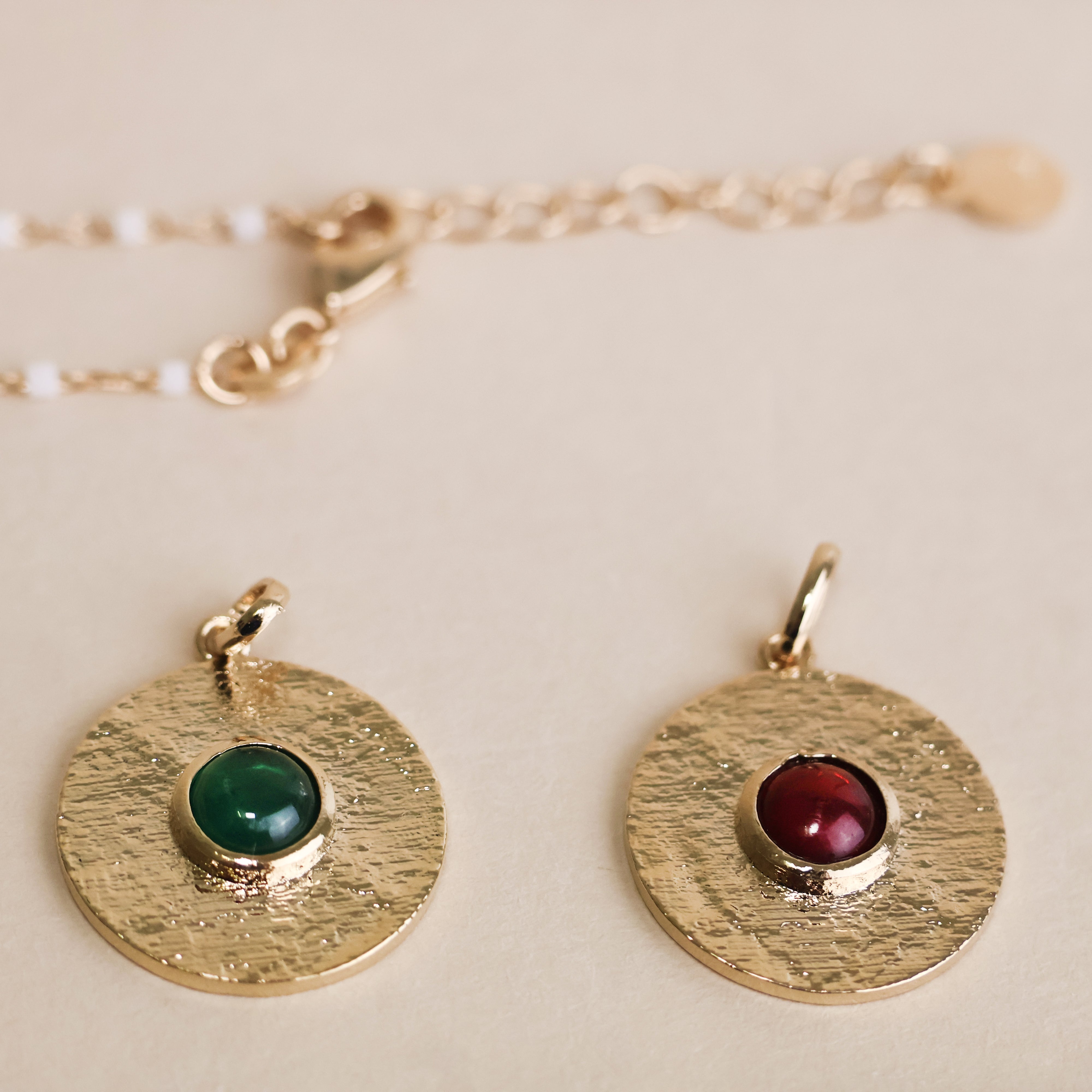 Pendentif Layana en plaqué or 18 carats – Un bijou élégant sublimé par une pierre turquoise, verte ou rouge et une finition dorée satinée. Son design raffiné permet de le personnaliser en l’accumulant avec une chaîne et une breloque. Diamètre : 18mm. Conçu en laiton avec un placage 3 microns et poinçon garantissant qualité et durabilité.